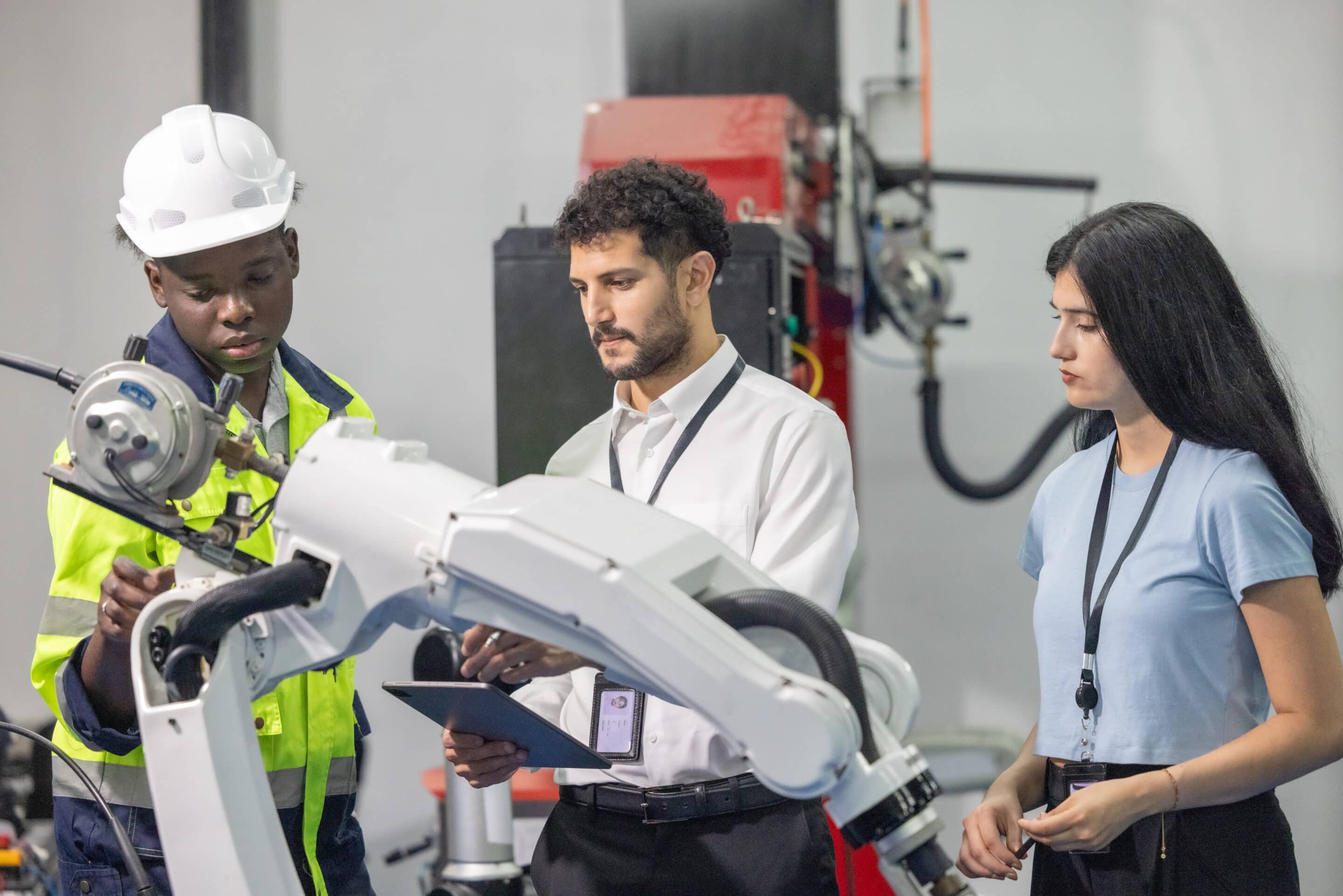 Three engineers analyzing OEE data on robotic hand demonstrating Industry 4.0 AI and IoT integration in manufacturing