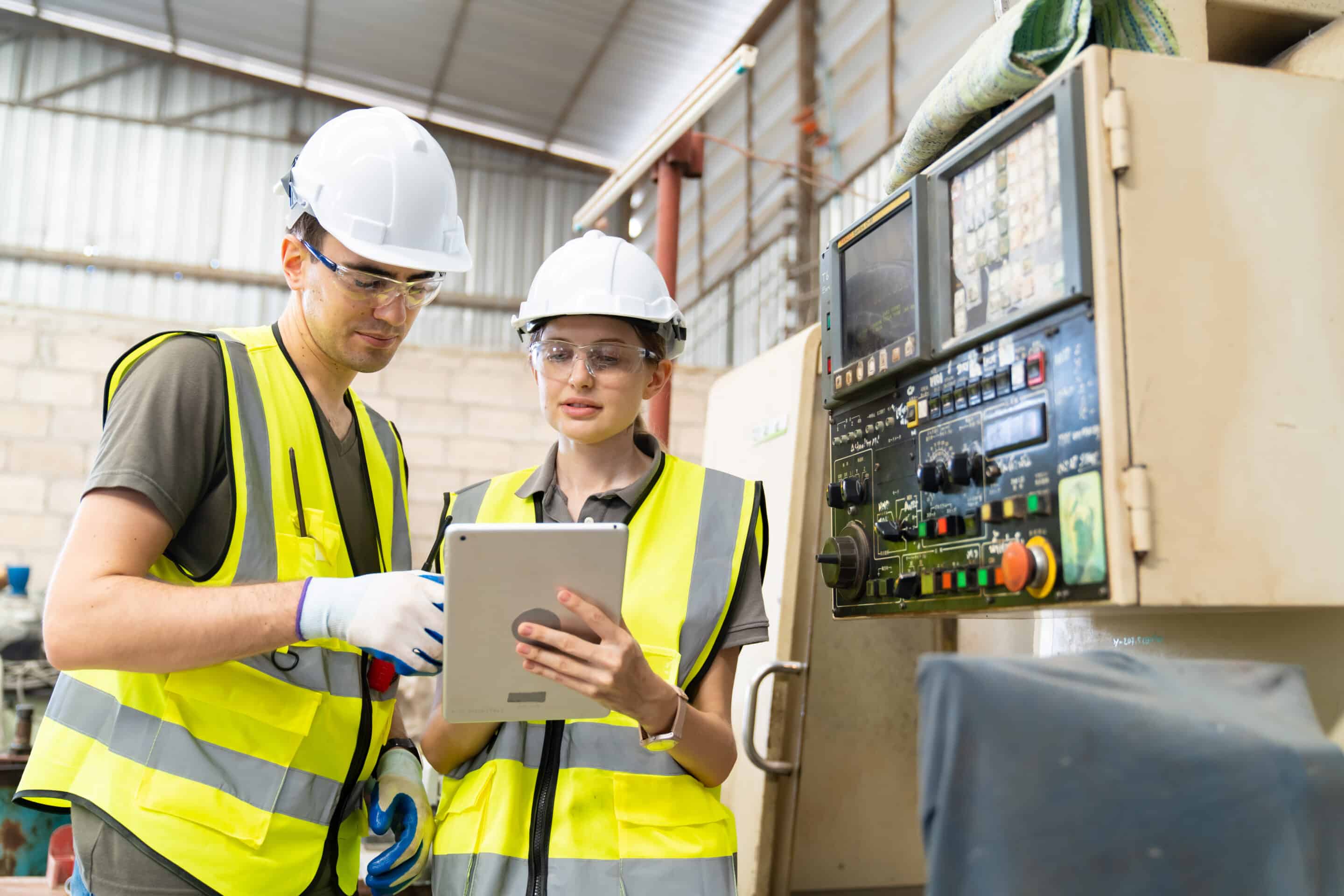 Opérateurs en usine utilisant tablette pour calcul OEE automatisé sur ligne de production industrielle