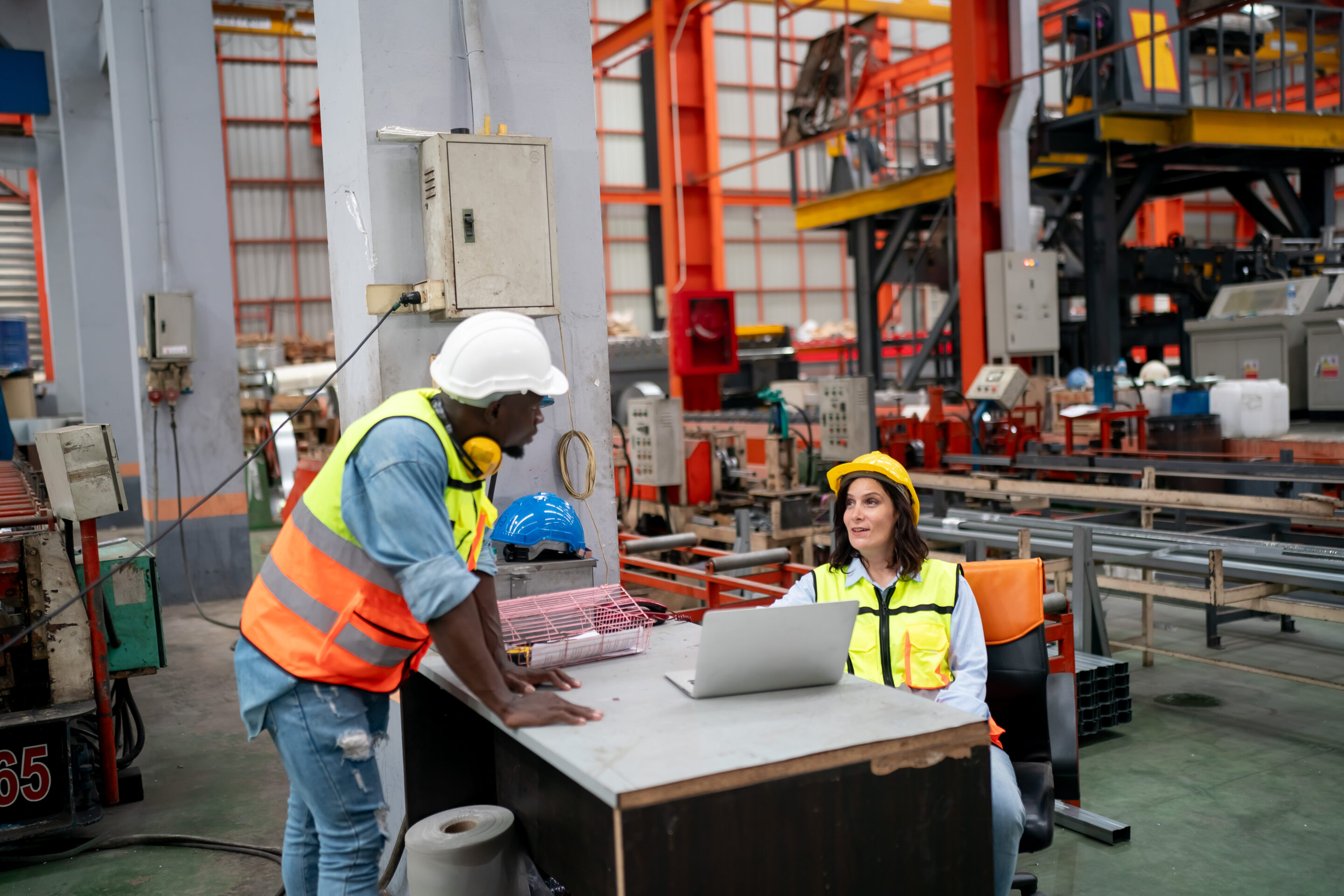Opérateurs industriels consultant des données OEE en temps réel sur ordinateur portable dans un atelier de production moderne