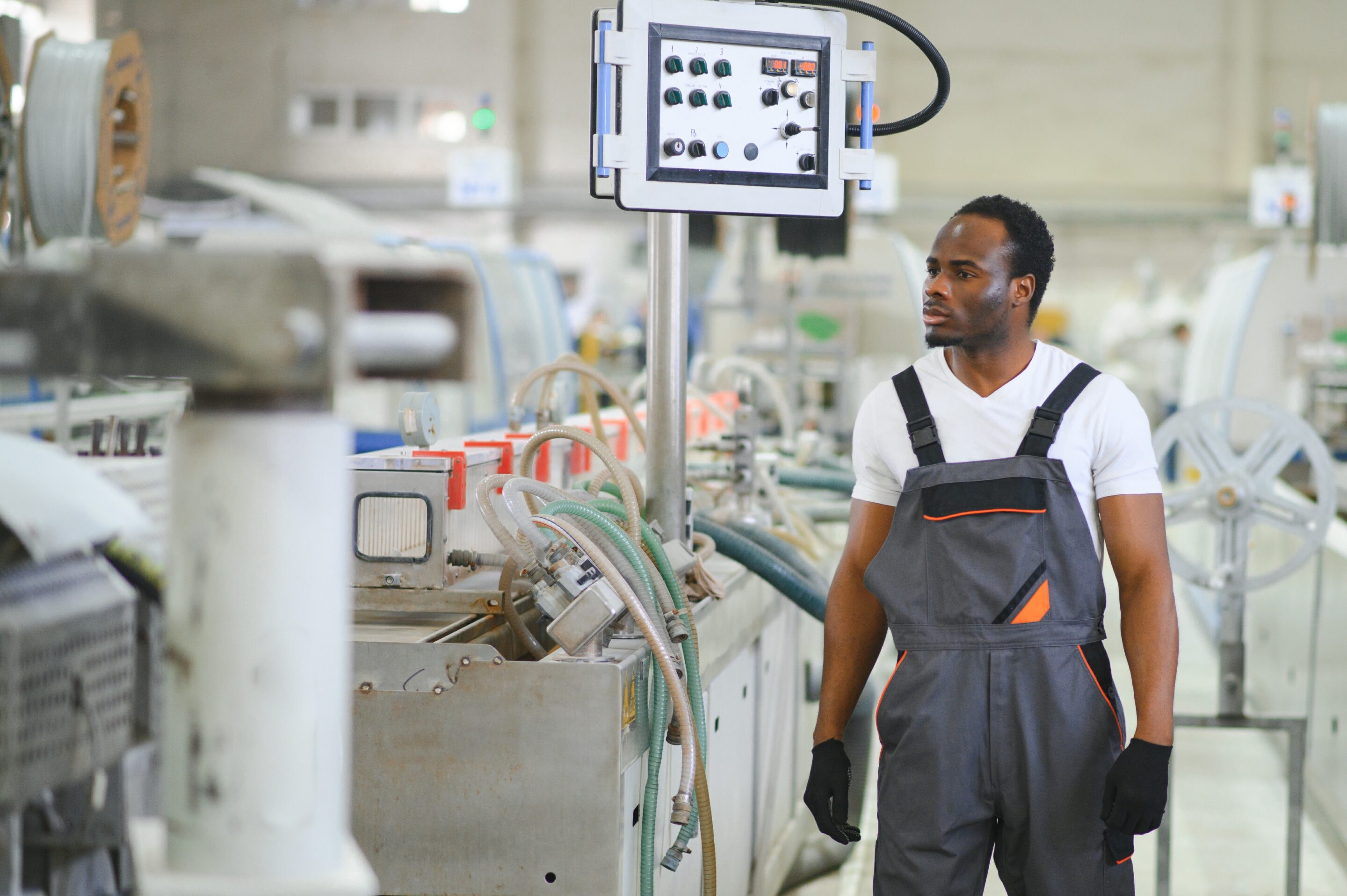 An African-American male worker in a plastic window frame factory Opérateur surveillant la performance OEE sur ligne de production en usine