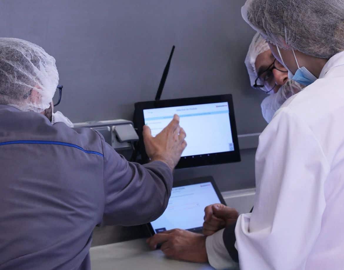 Opérateurs en environnement agroalimentaire consultant un tableau de bord de suivi de production sur écran tactile